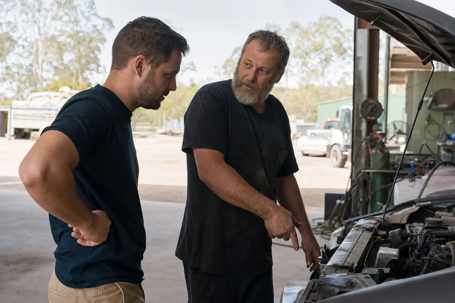 Mechanic talking with a customer beside a car in an open workshop