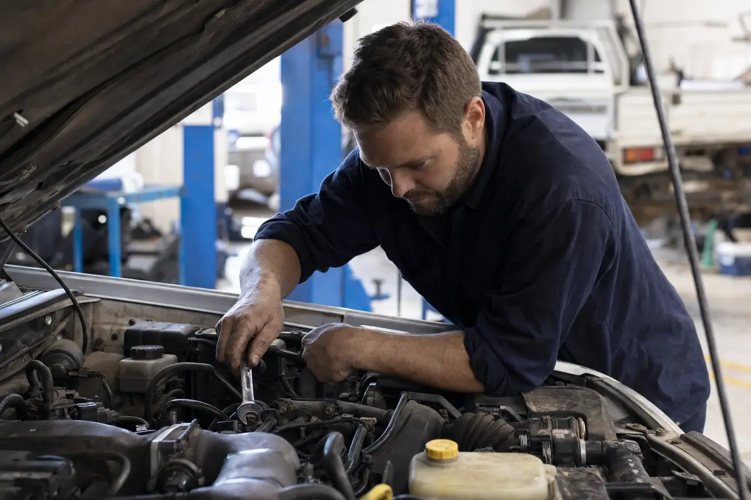 Motor mechanic working on a car engine in a clean Australian workshop