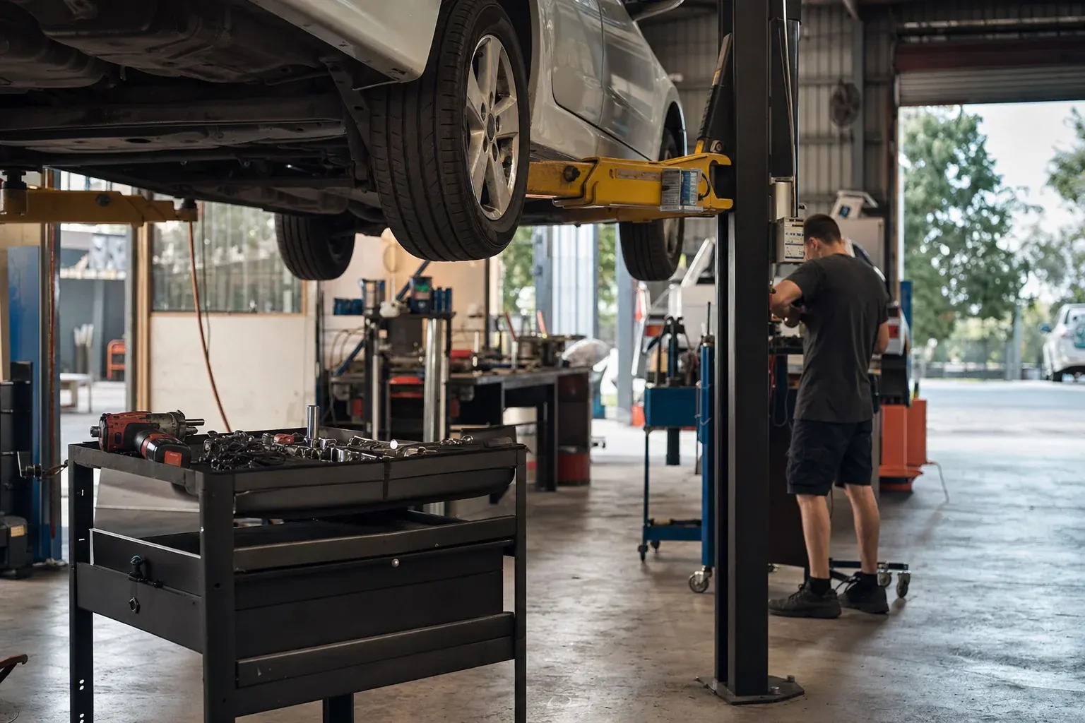 Auto electrician working on vehicle wiring harnesses in a well-lit workshop